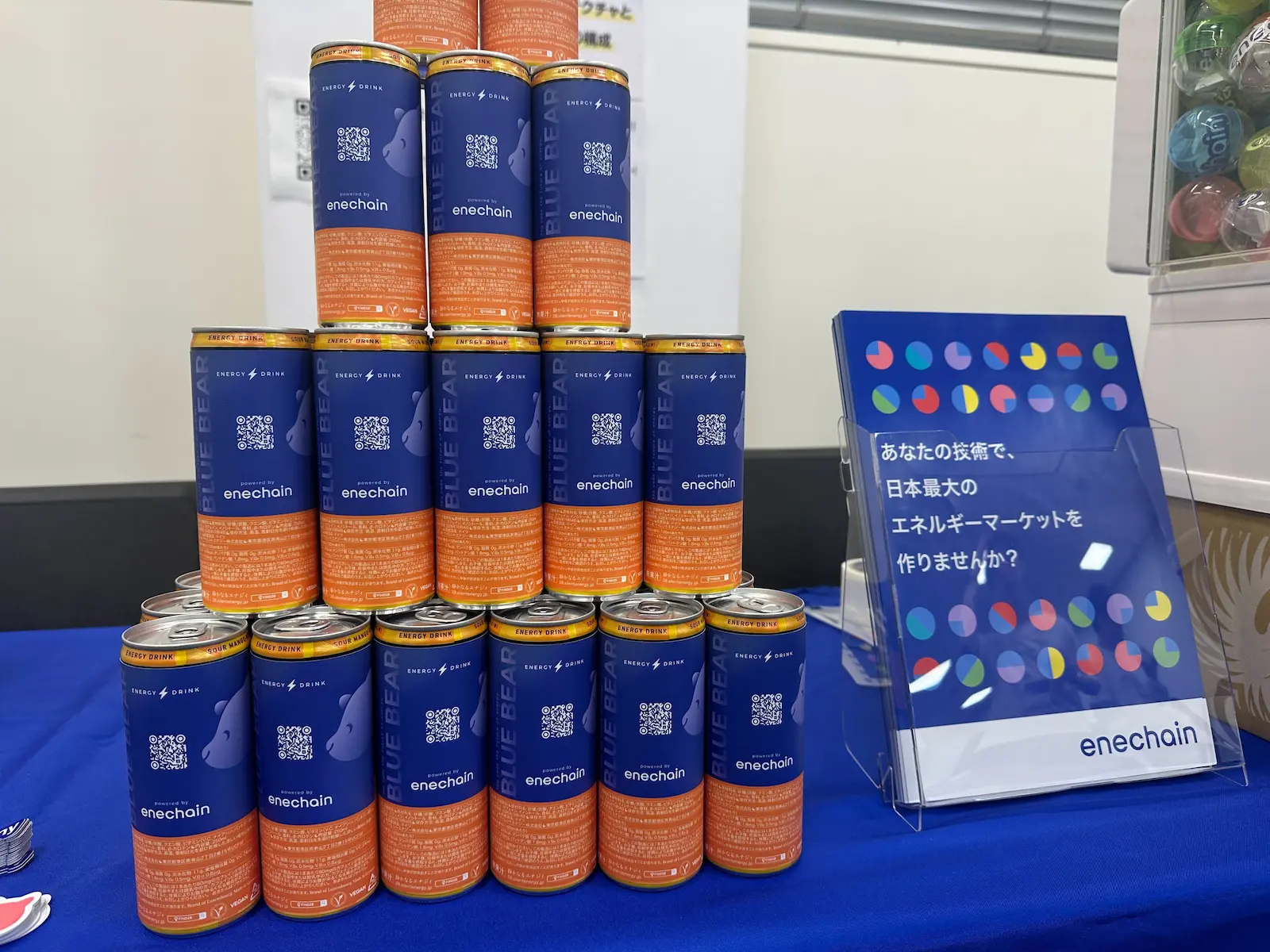 enechain社の展示ブースの様子。28 BLACKオリジナルラベルエナジードリンクがピラミッド状に積み上げられ、ガチャガチャマシンとともに展示されている